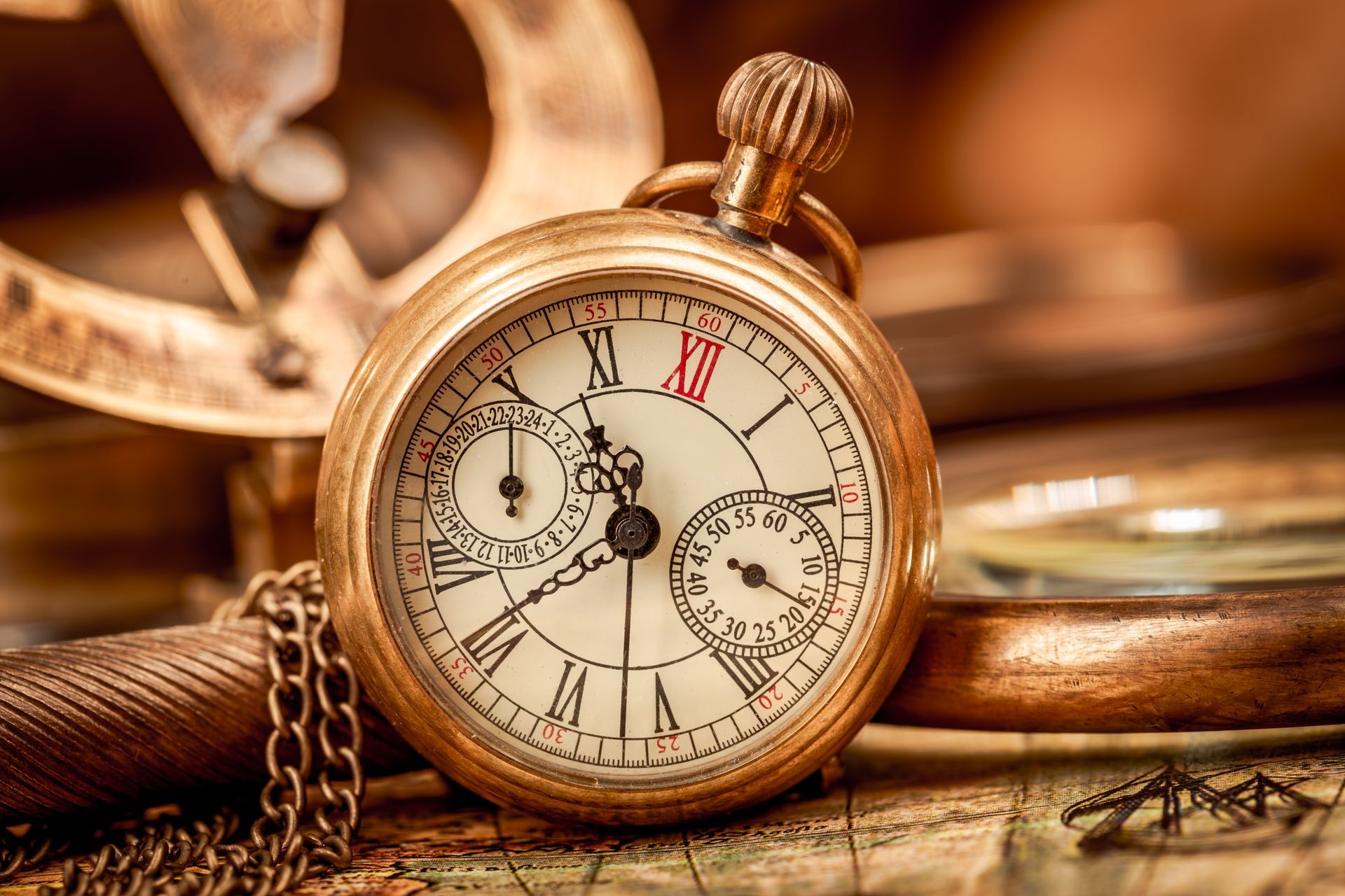 An old pocket watch is sitting on a map next to a magnifying glass.