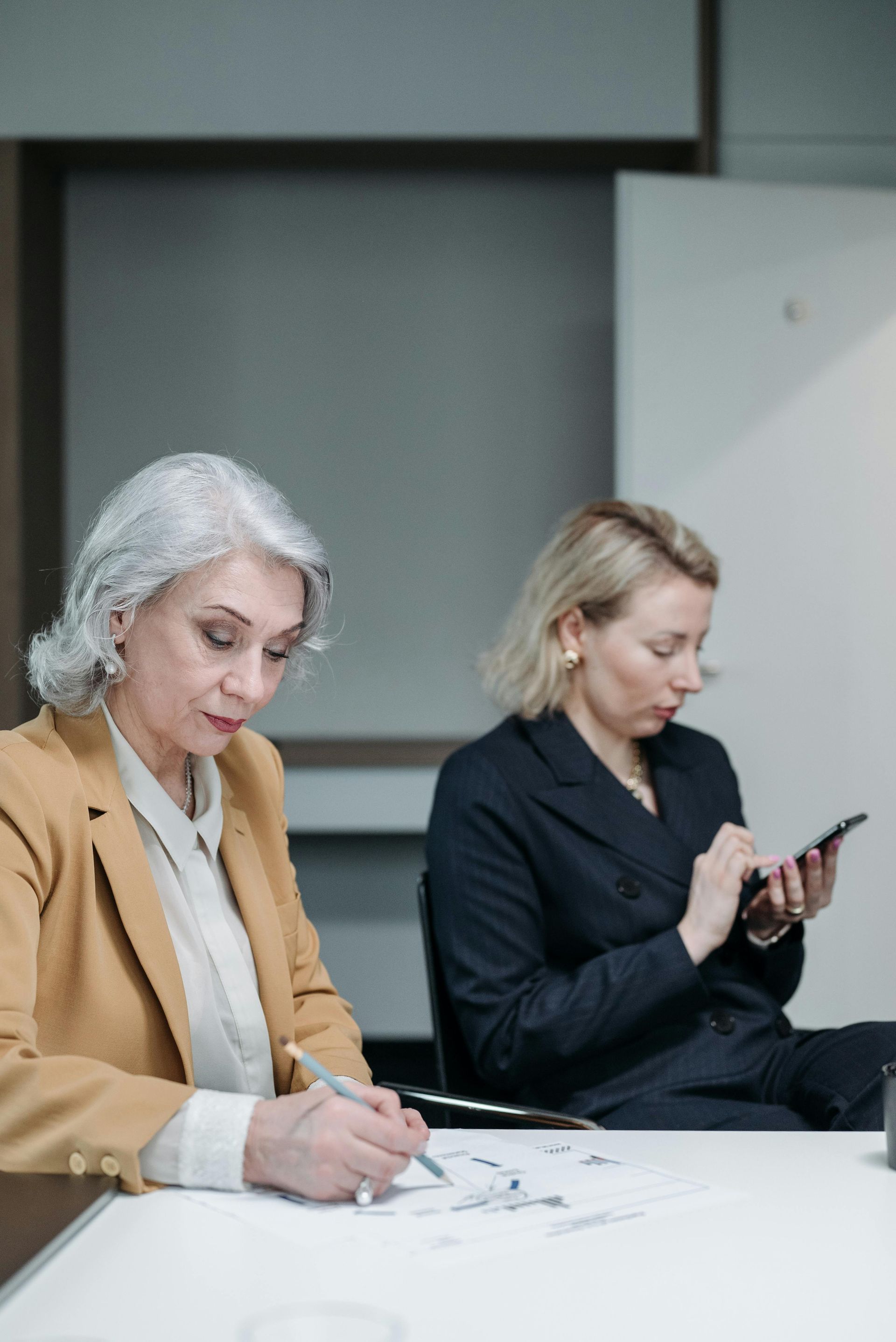 A woman is standing in a hallway looking at her cell phone.