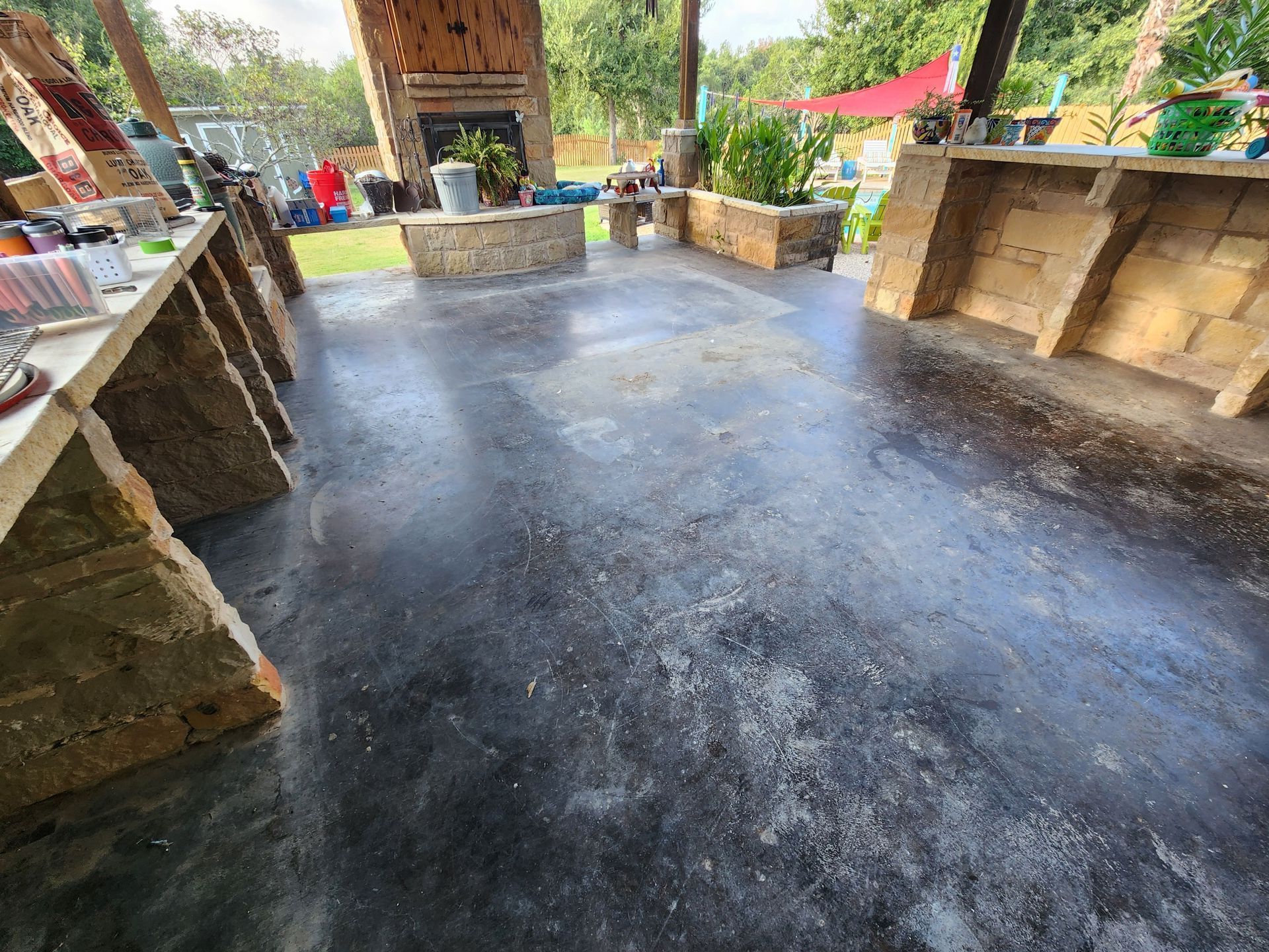 A patio with a black concrete floor and a fireplace.