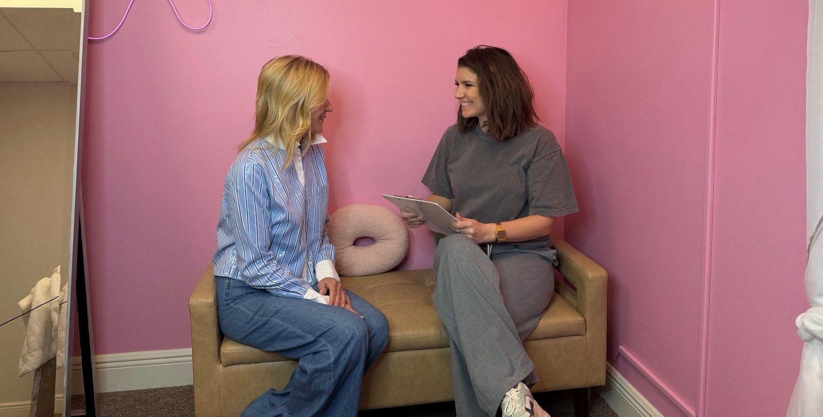 Aesthetician's studio: white chairs, treatment bed, mirrors, plants, and light wood floor.