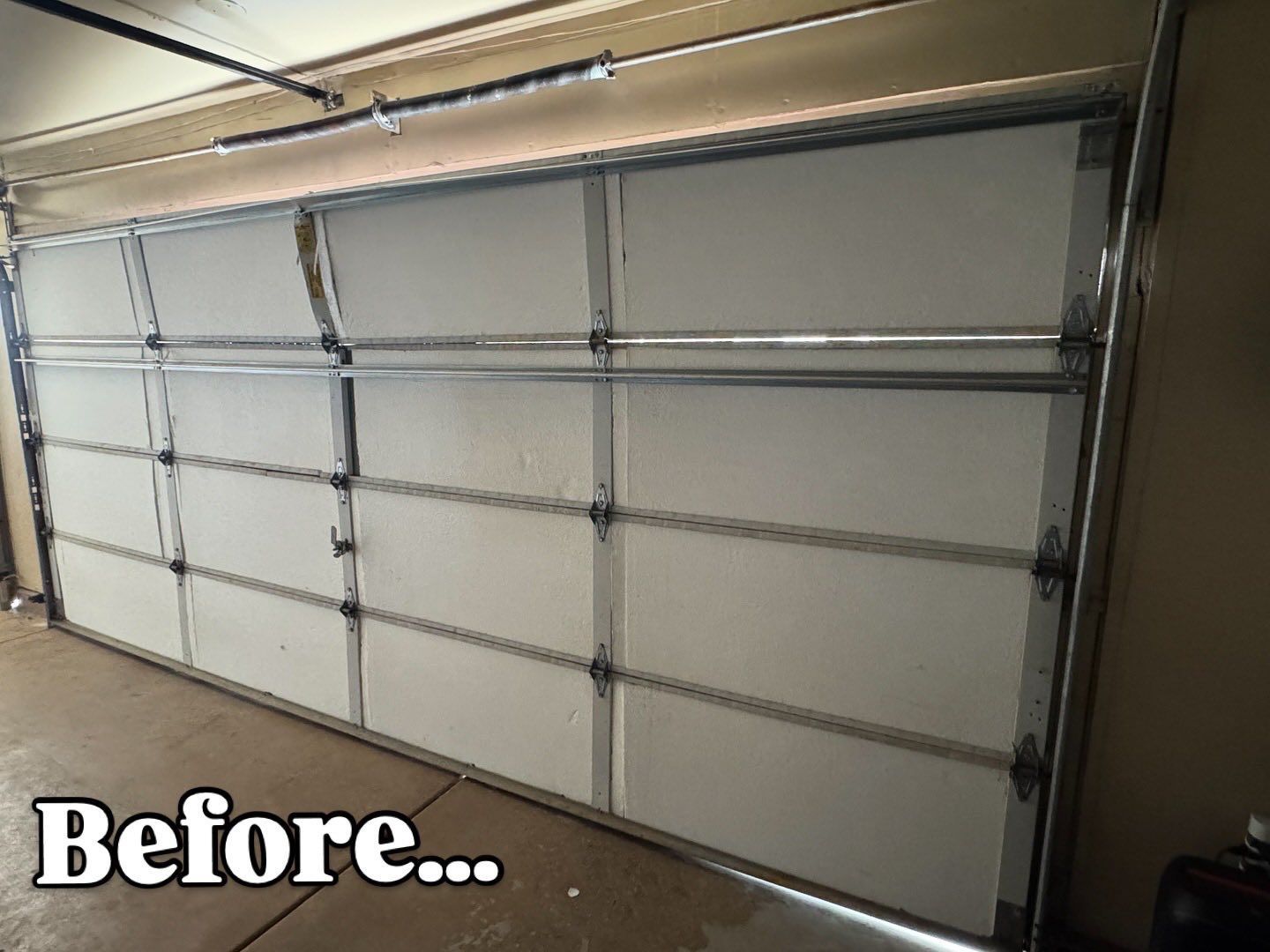 Garage door, white panels, silver trim, closed. 