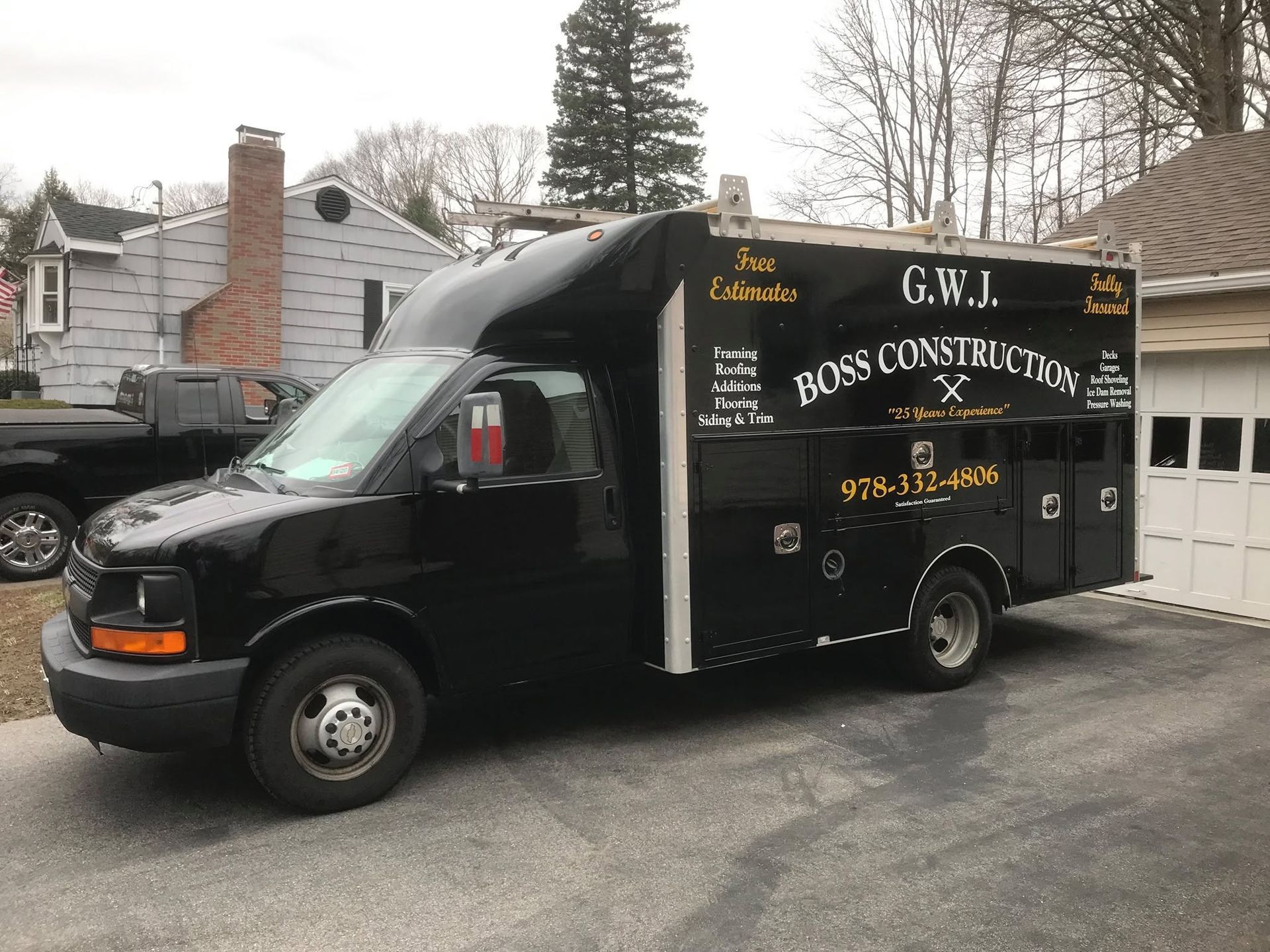 A black construction van is parked in front of a garage.