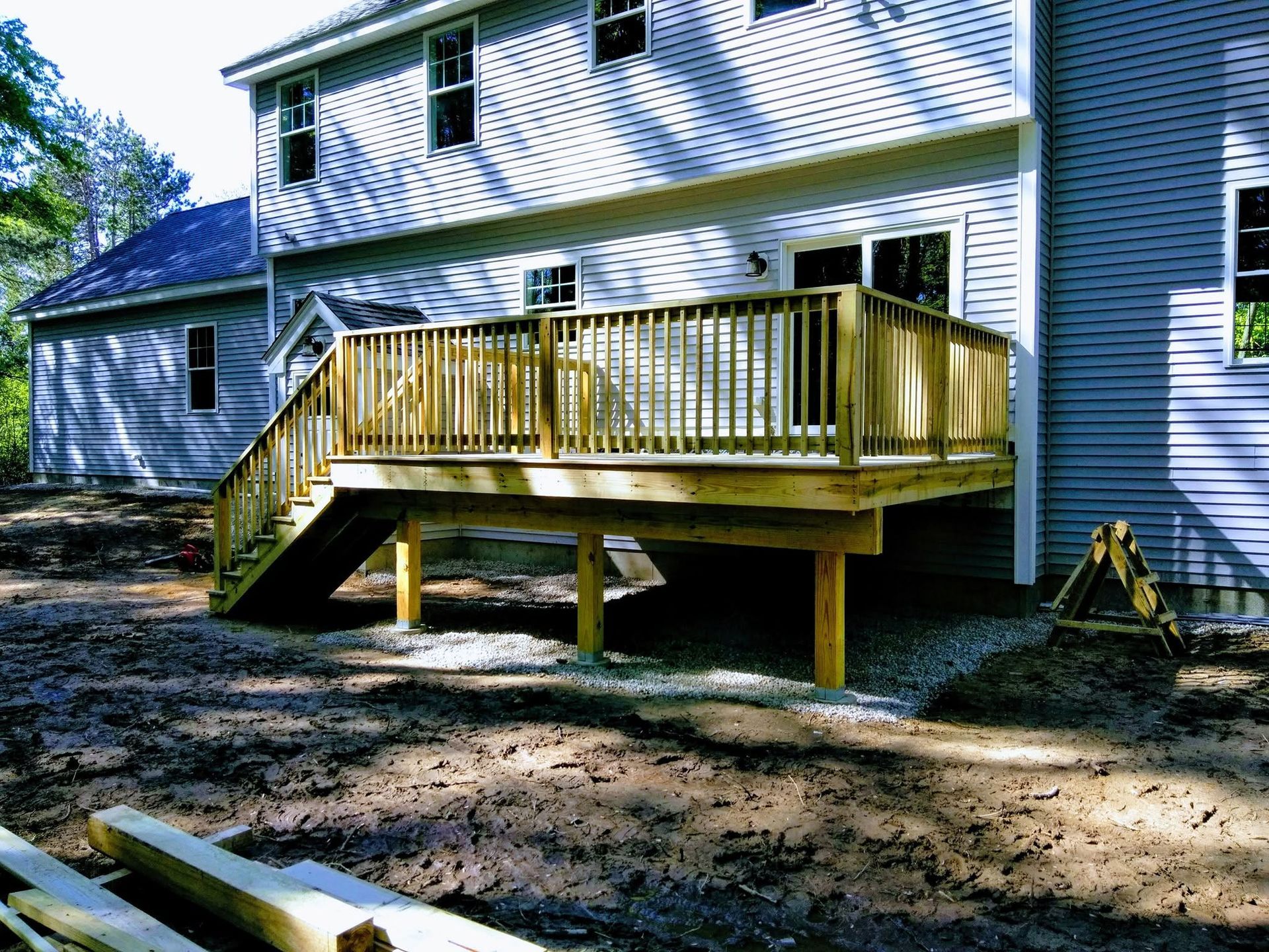 A wooden deck with stairs is being built in front of a house.