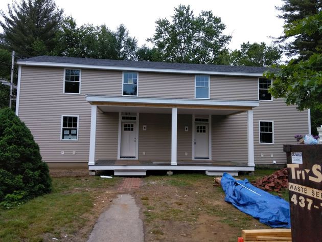 A gray house with a white garage door and a porch.