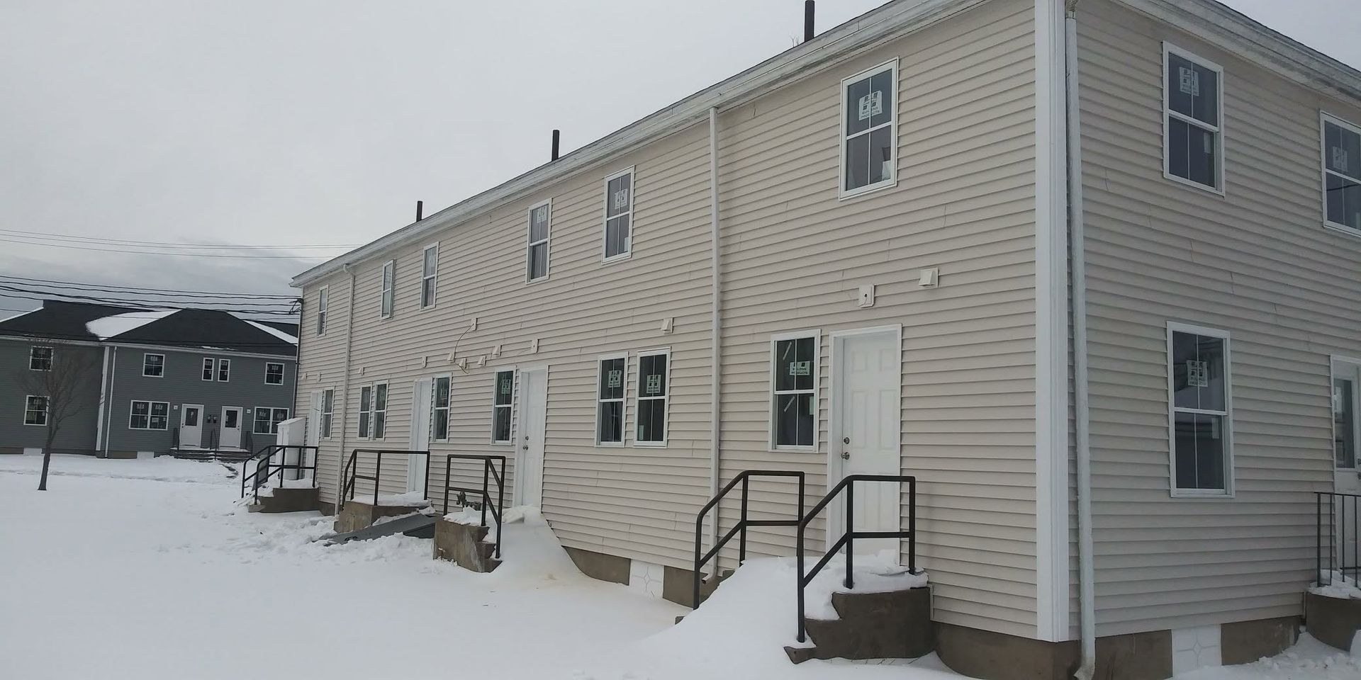 A large white house with stairs leading up to it is covered in snow.