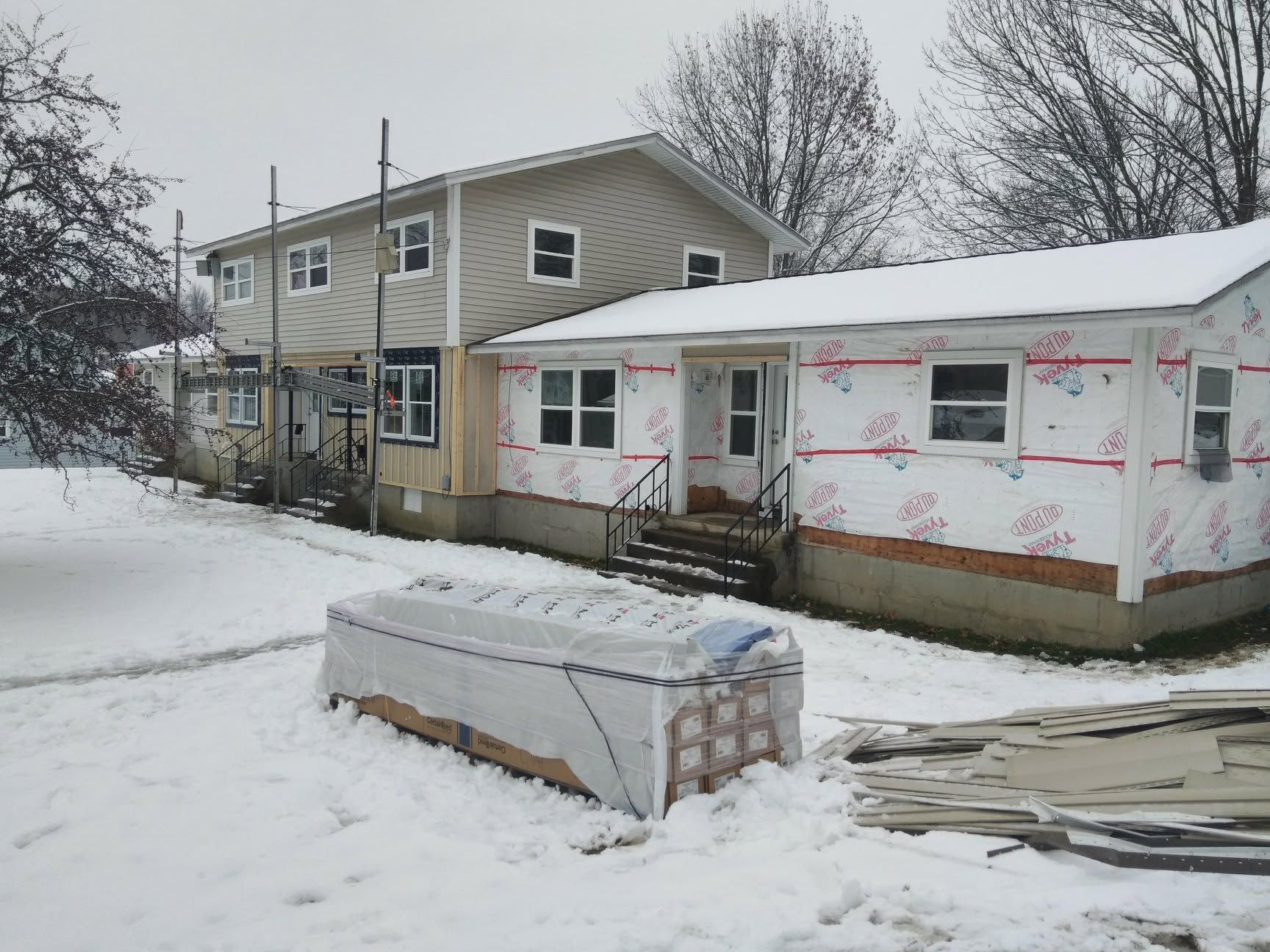 A house with a lot of snow on the ground in front of it