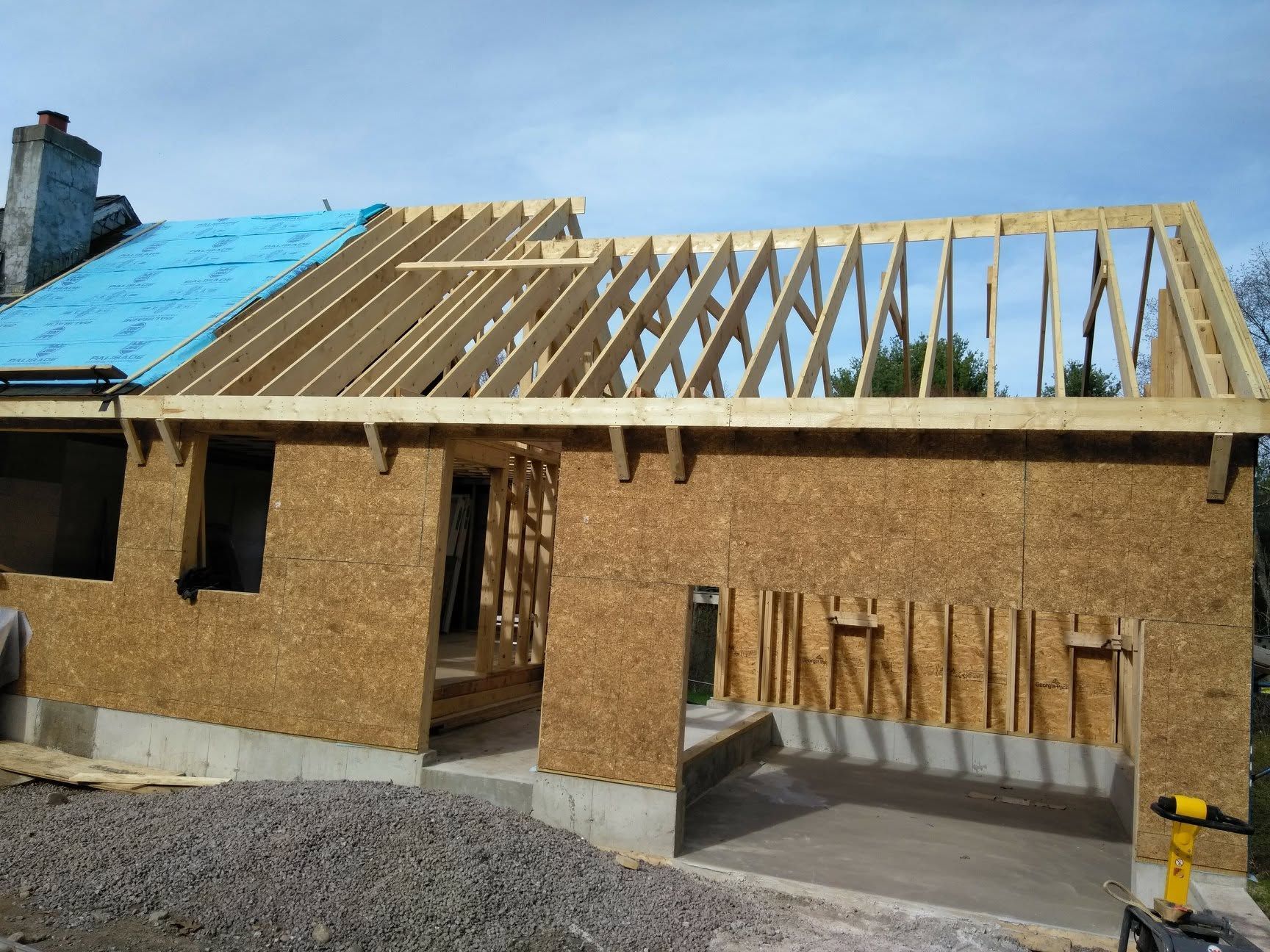 A house is being built with wooden beams and a blue roof.