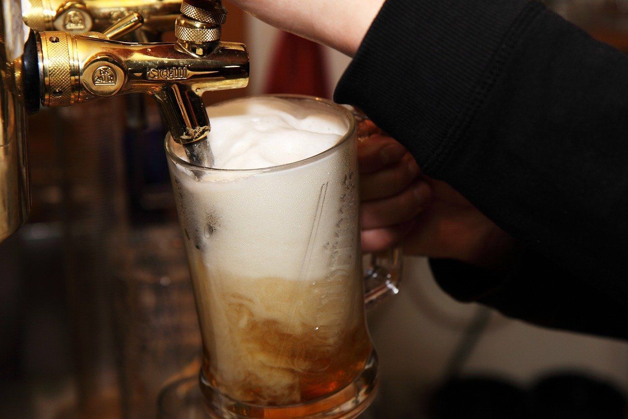 A person is pouring beer into a glass from a tap