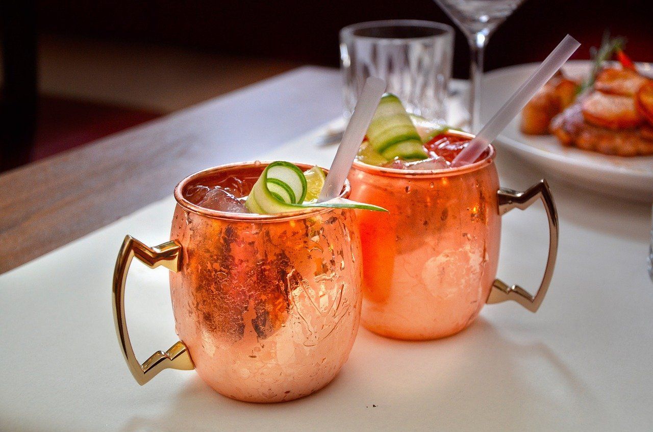 Two copper mugs filled with a drink on a table.