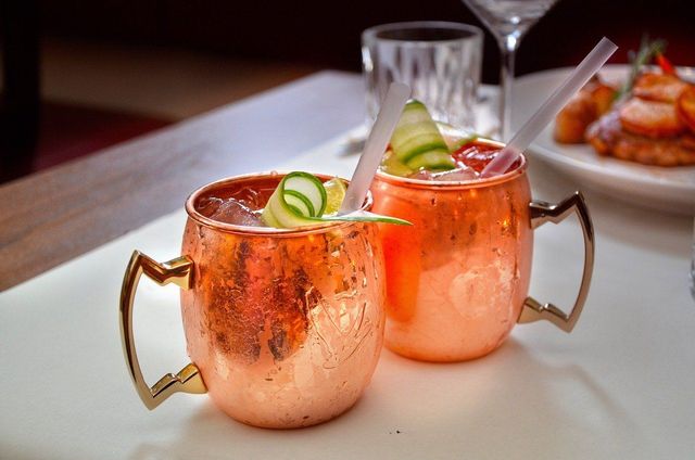 Two copper mugs filled with a drink on a table.