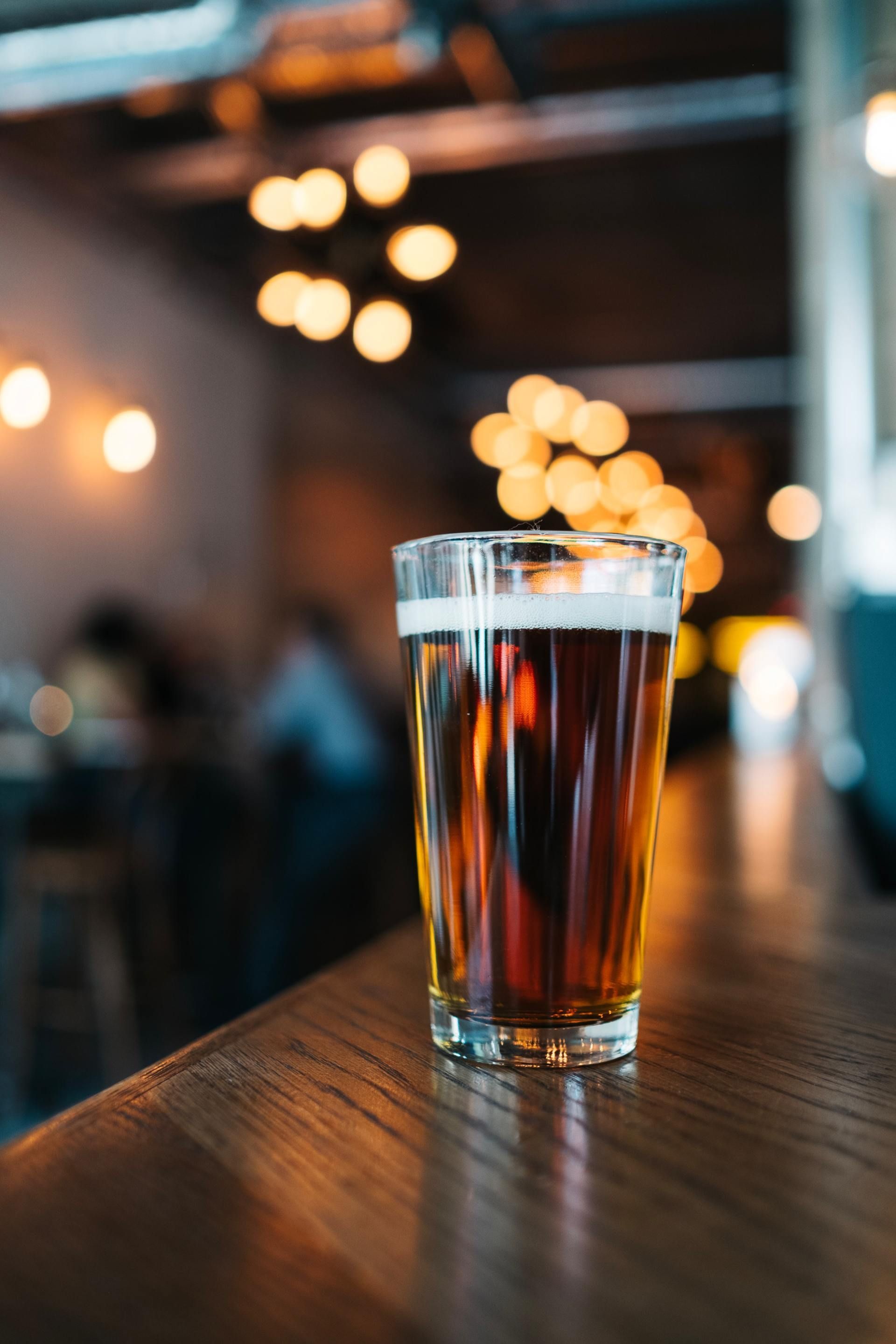 A glass of beer is sitting on a wooden table.