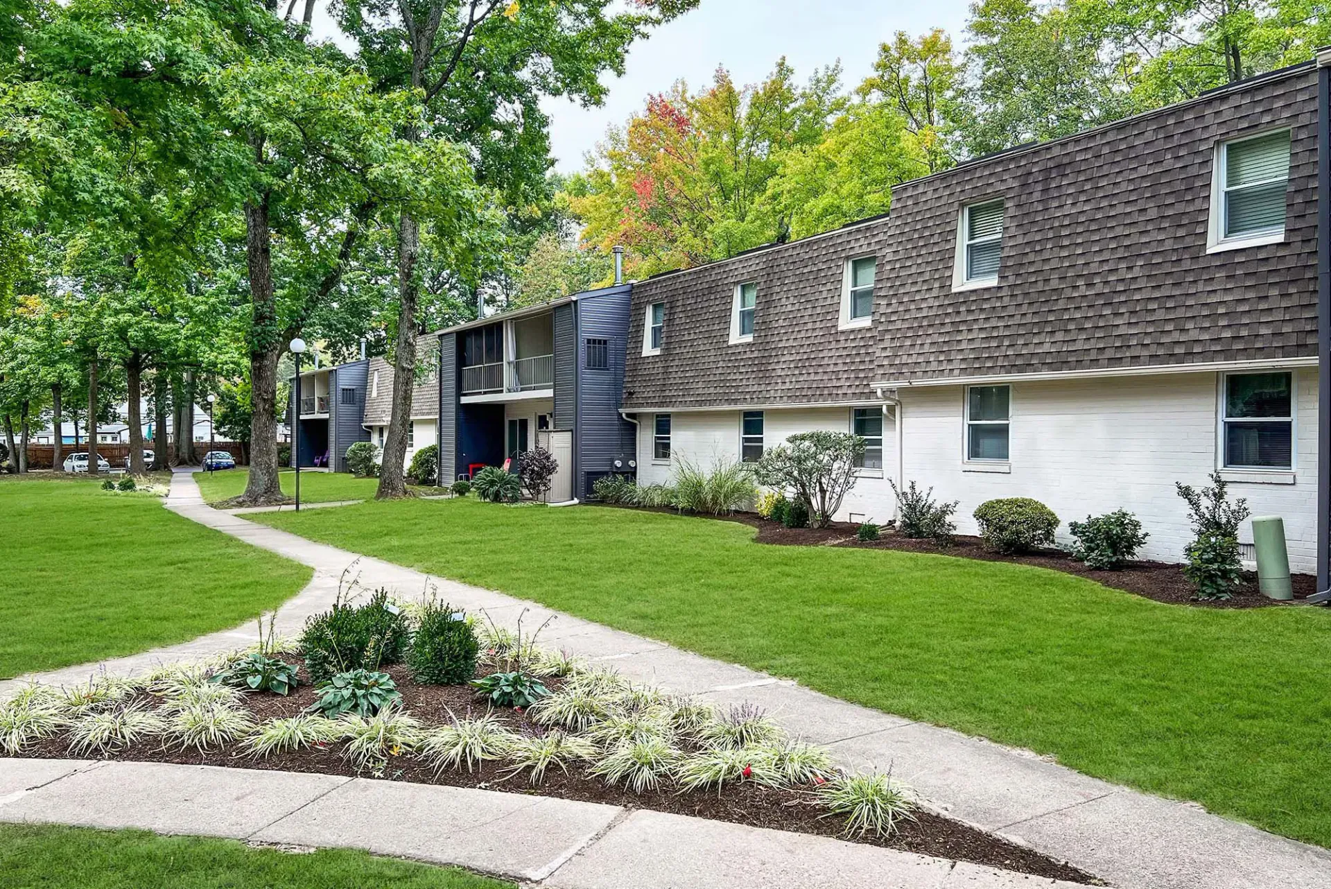 Exterior view of apartment buildings with a green lawn and winding sidewalk.