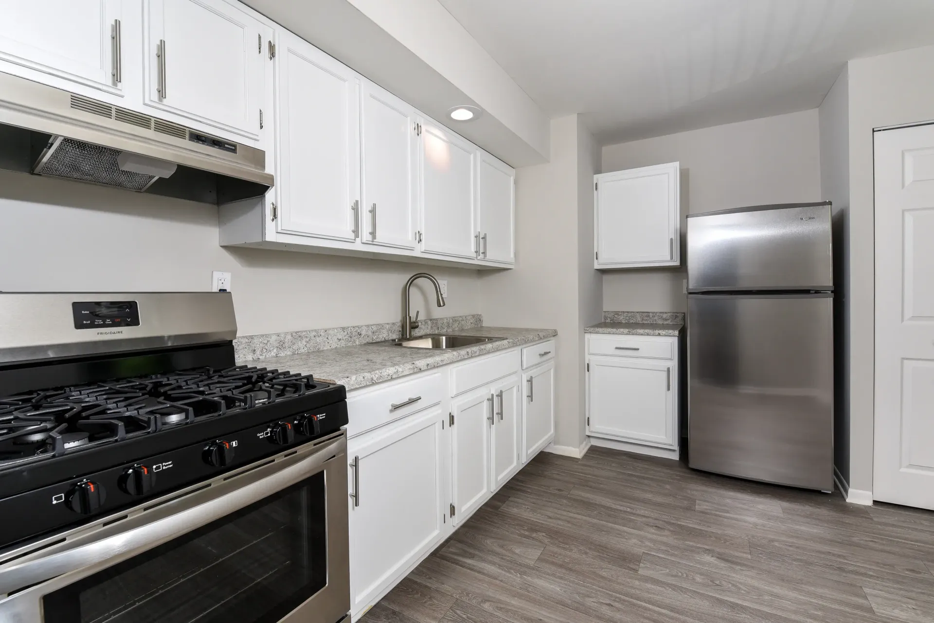 Kitchen with white cabinets, granite countertops, stainless steel stove and refrigerator.