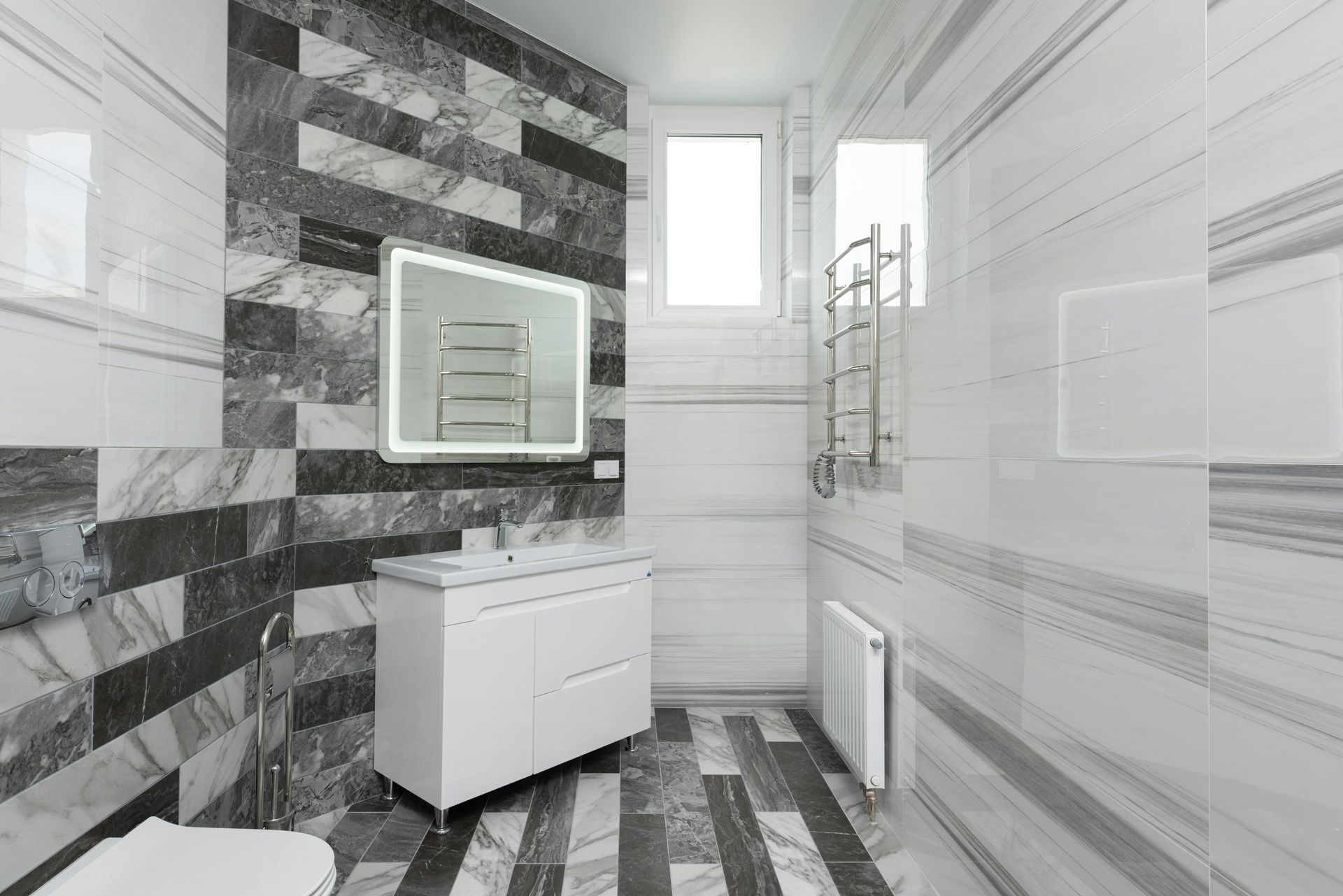 A bathroom with a toilet , sink , mirror and towel rack.