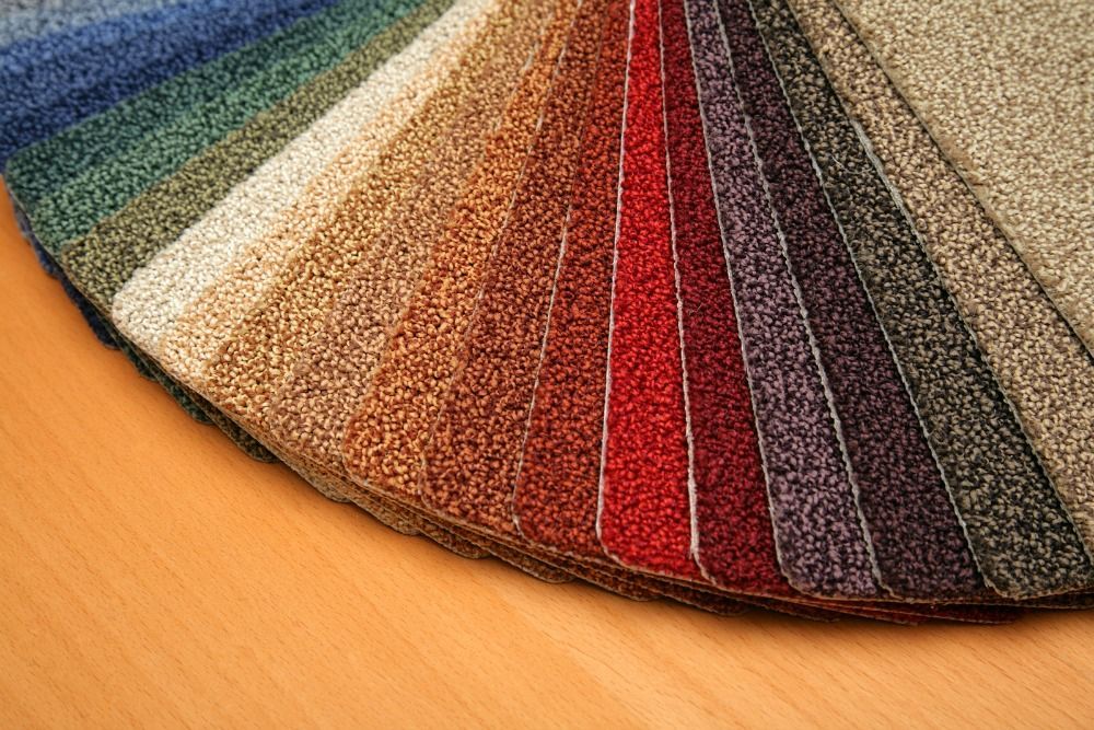 Carpet samples in various colors fanned out on a wooden surface.
