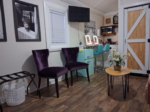A waiting area featuring two purple velvet chairs, a small round table with flowers, and a turquoise cabinet.