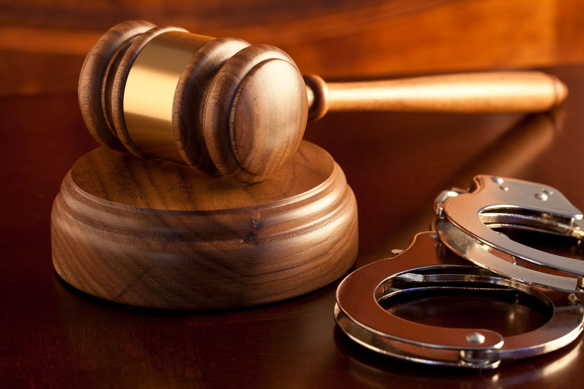 Wooden gavel on block next to handcuffs, suggesting a legal or justice context.