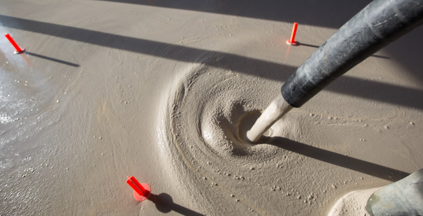 Une personne verse du béton dans un trou dans le sol.