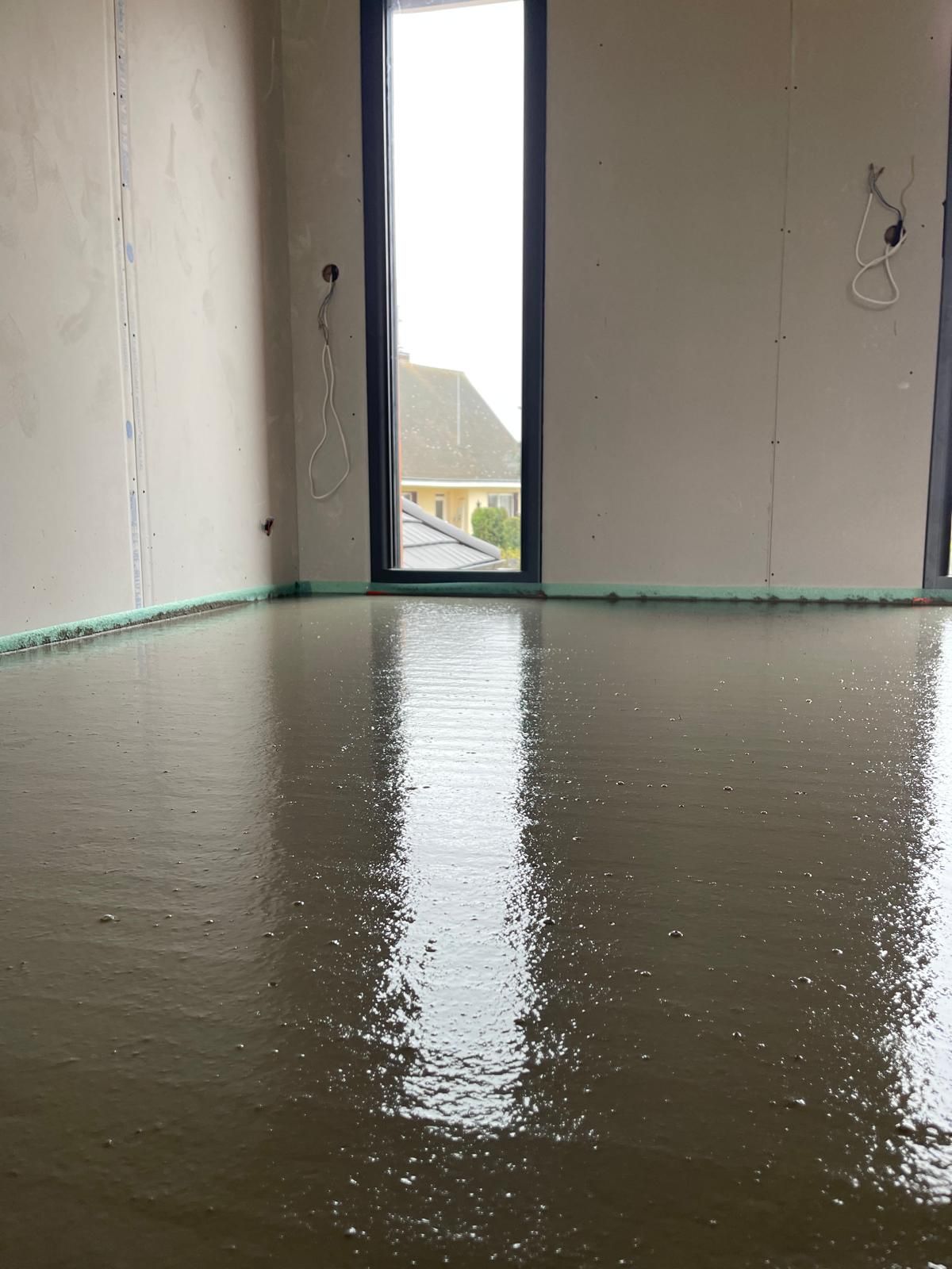 Une pièce avec une fenêtre et un sol en béton.