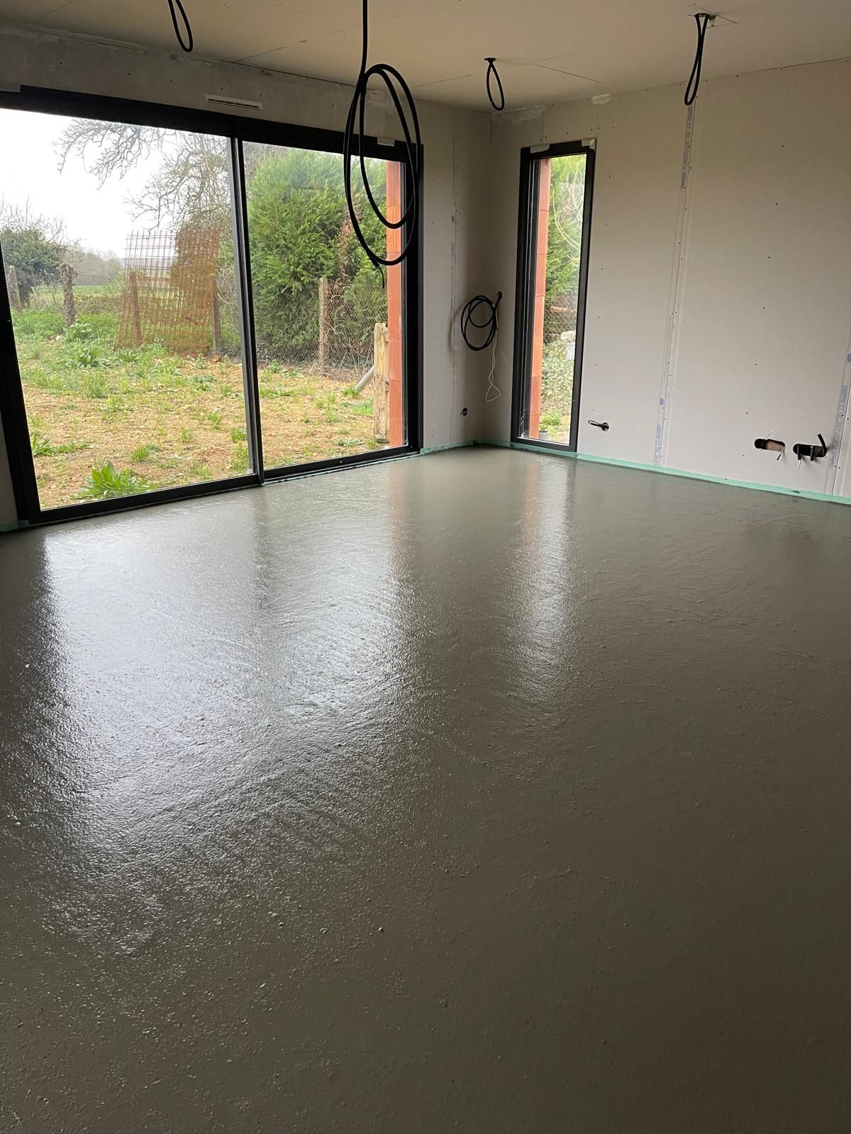 Une pièce avec un sol en béton et une grande fenêtre.