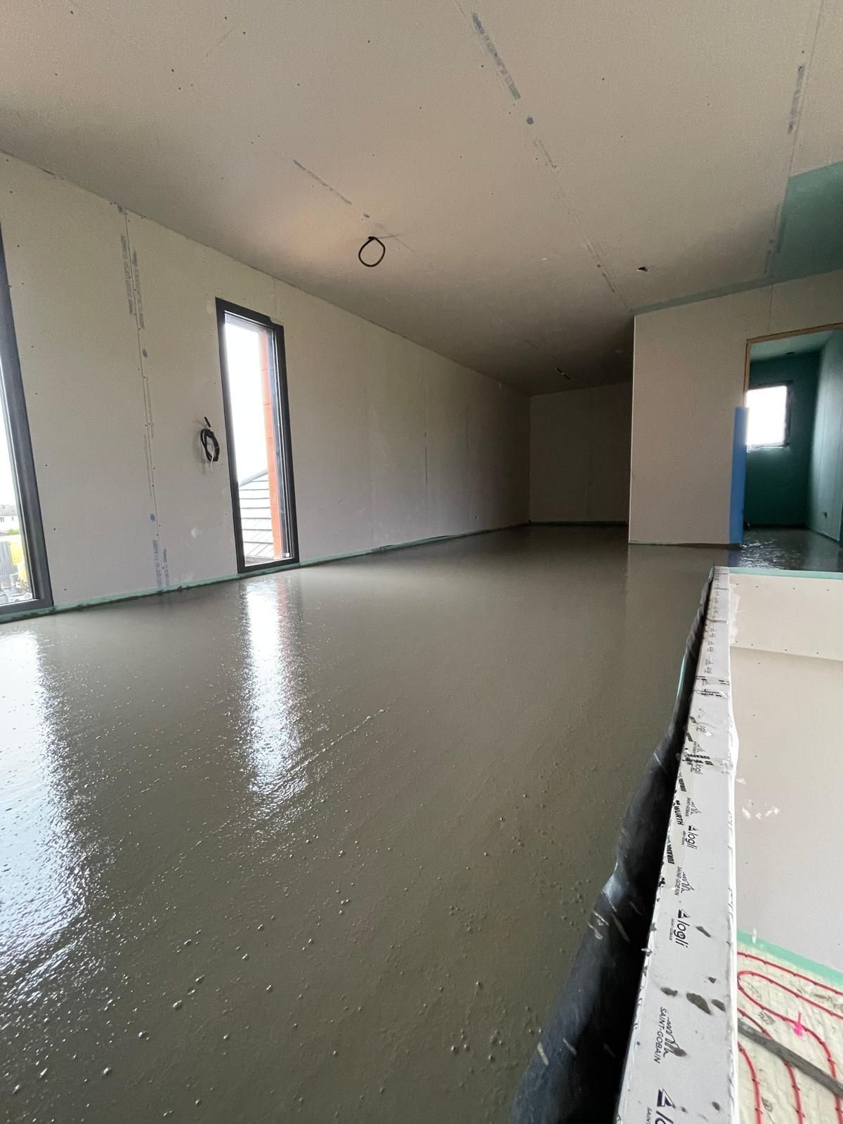 Une grande pièce vide avec un sol en béton et des murs blancs.