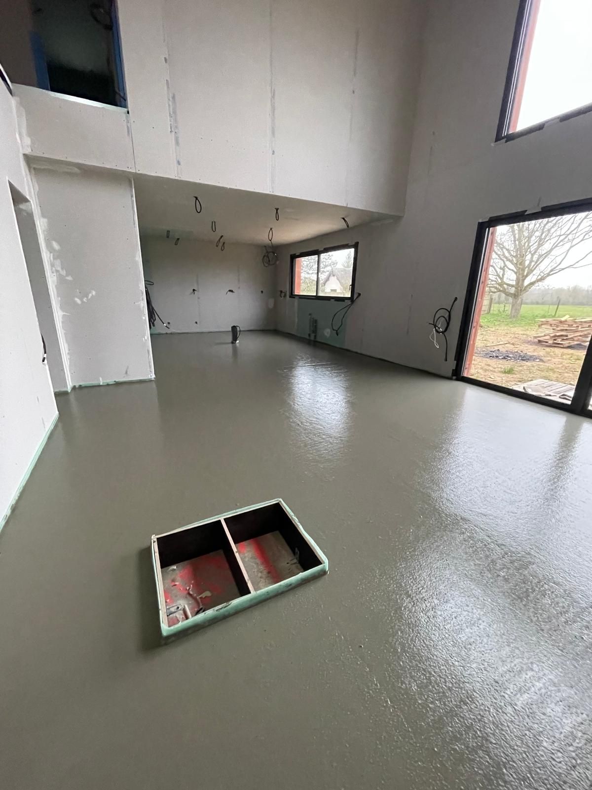 Une grande pièce avec un sol en béton et une fenêtre.