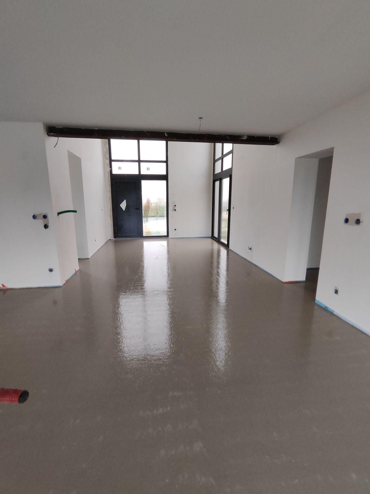 Une grande pièce vide avec un sol en béton et des murs blancs