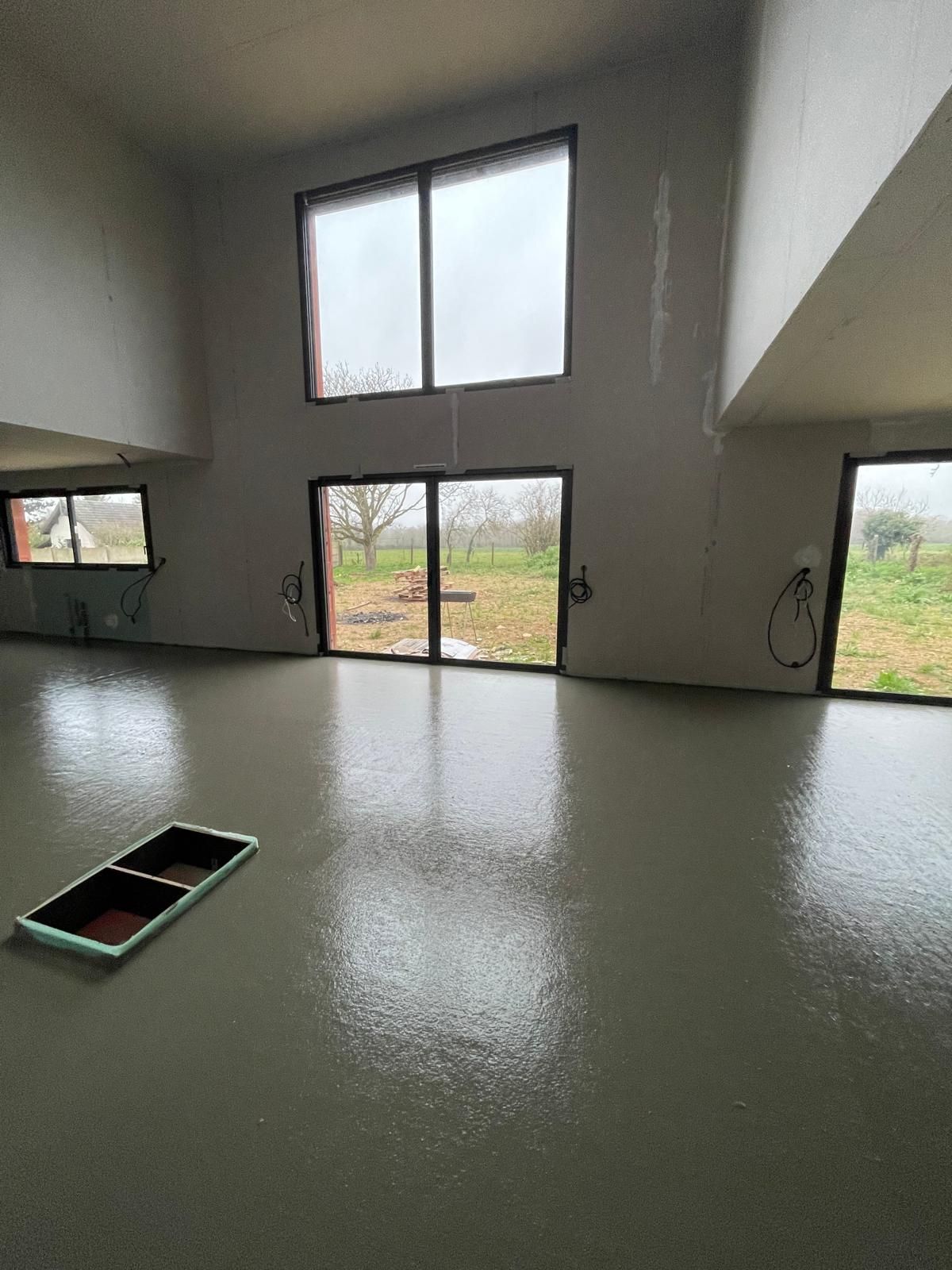 Une grande pièce avec beaucoup de fenêtres et un sol en béton.