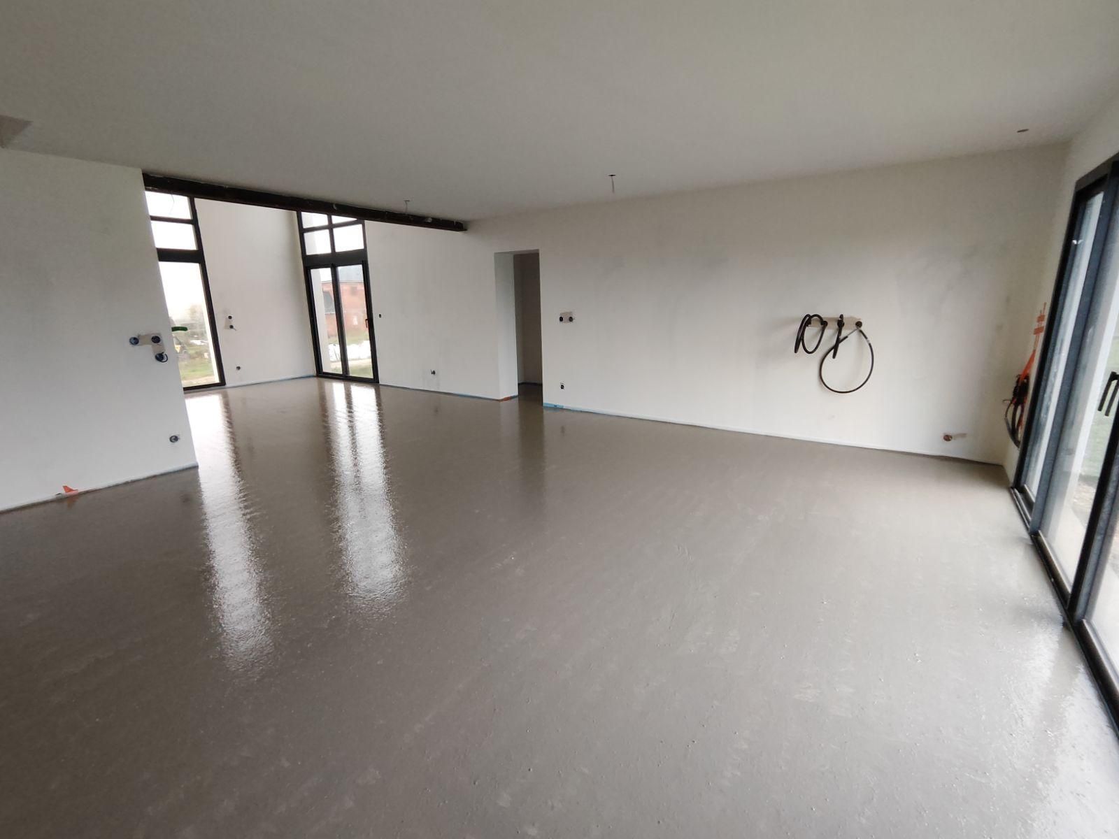 Une grande pièce vide avec un sol en béton et des murs blancs.