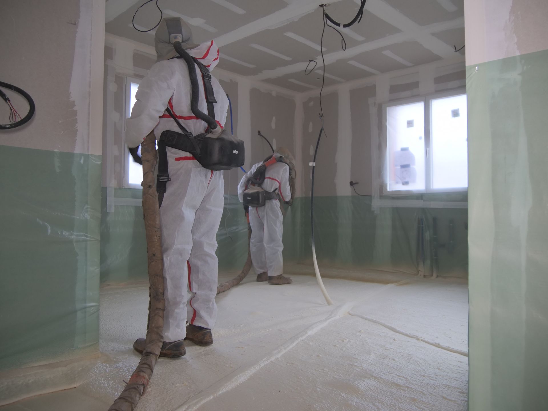 Un homme en combinaison de protection pulvérise de la mousse sur le sol