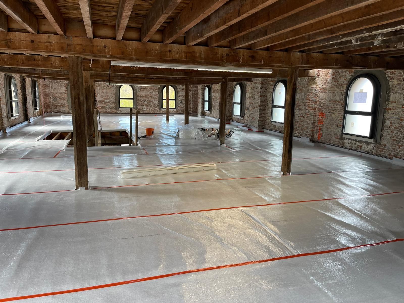 Une grande pièce avec un plafond en bois et une bâche blanche au sol.