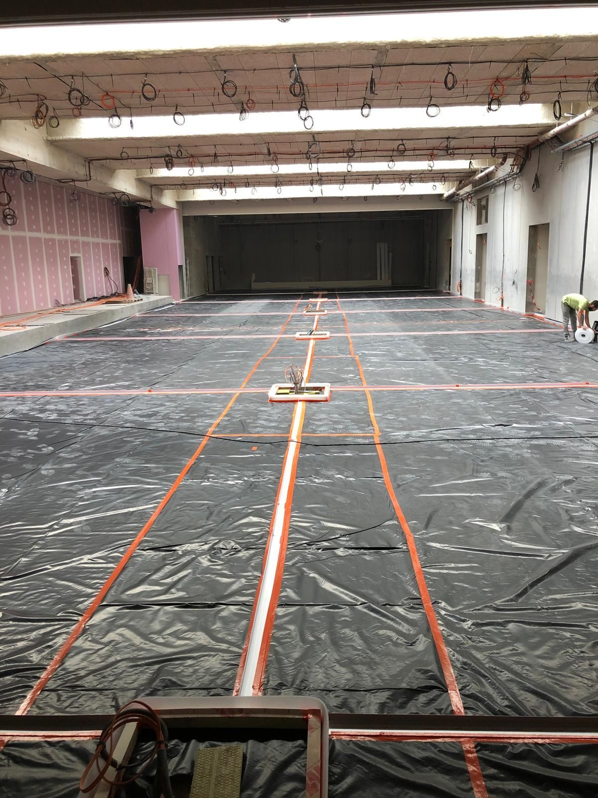 Une grande pièce vide avec une bâche noire sur le sol.