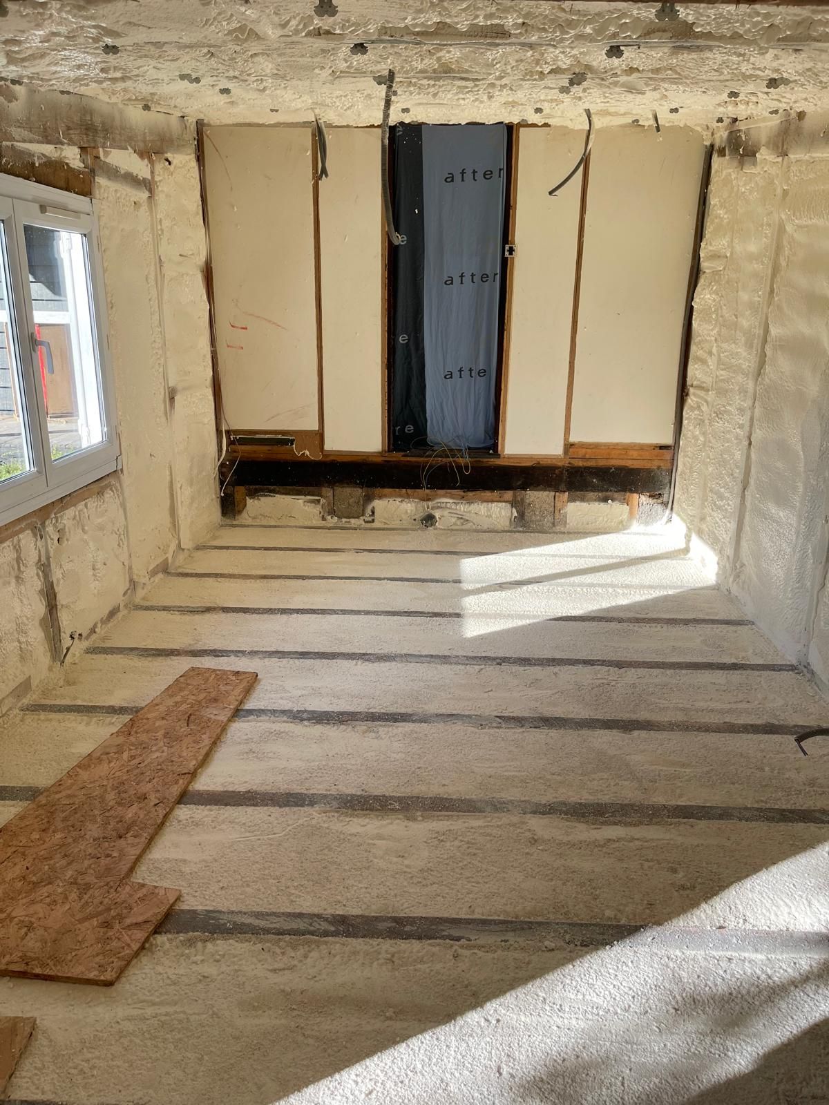 Une pièce avec un plancher en bois et une fenêtre.