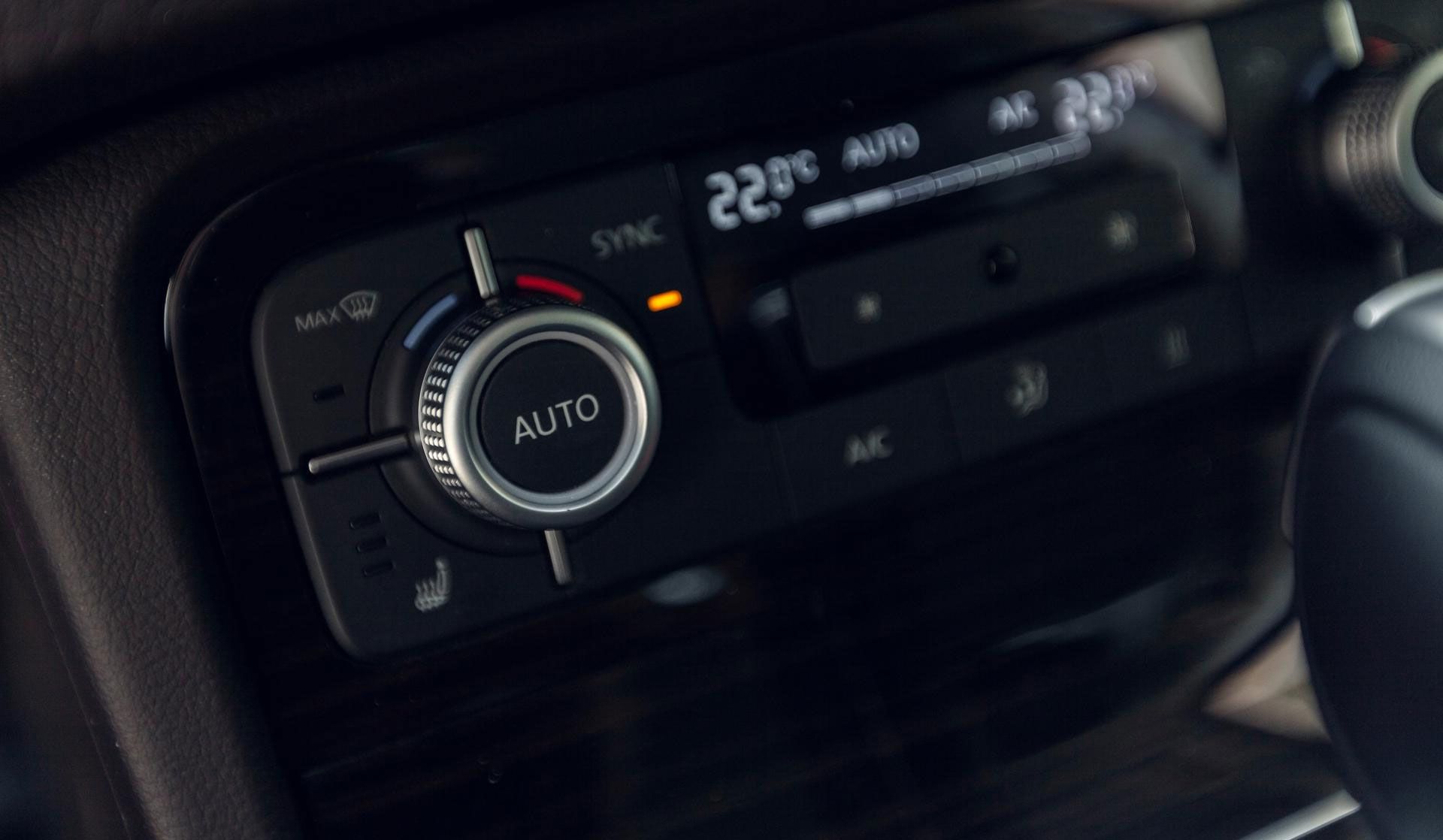Car's climate control panel: digital display, temperature controls, and dials for airflow and auto settings.