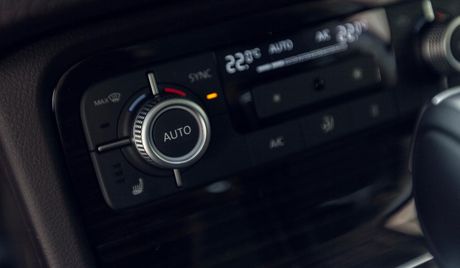 Car's climate control panel with digital display, temperature dials, and buttons for AC and other settings.