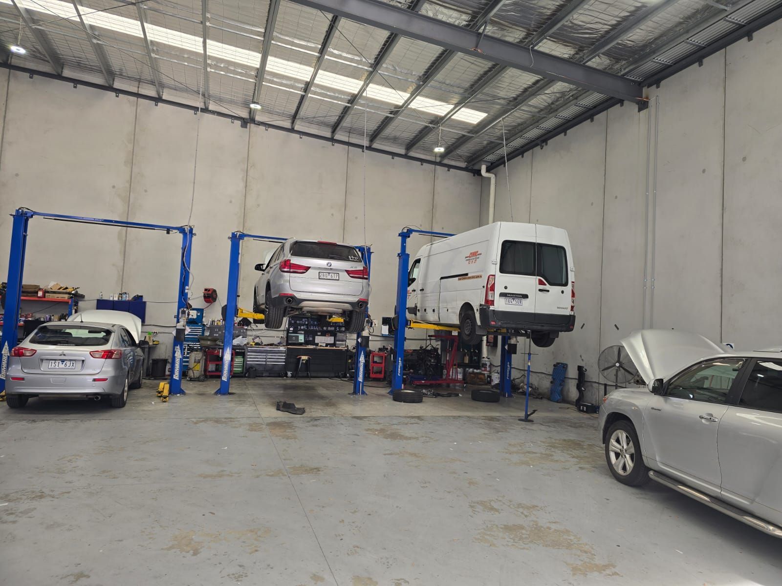 Cars in a garage being worked on with lifts.