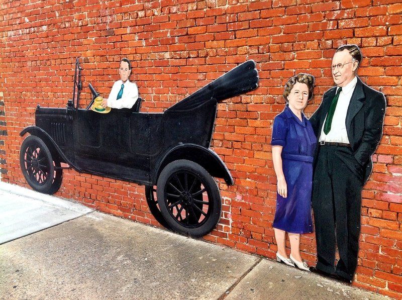 A painting of a man and woman standing next to a car on a brick wall