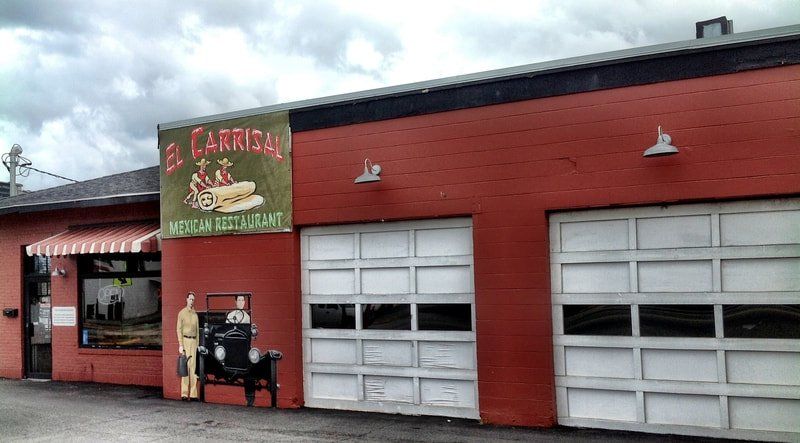 A red building with white garage doors and a sign that says carrion