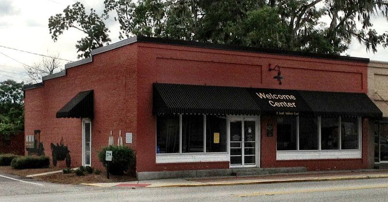 A red building with a black awning that says welcome