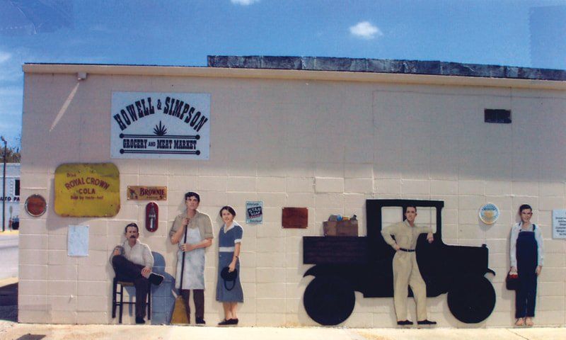 A mural on the side of a building shows people and a truck