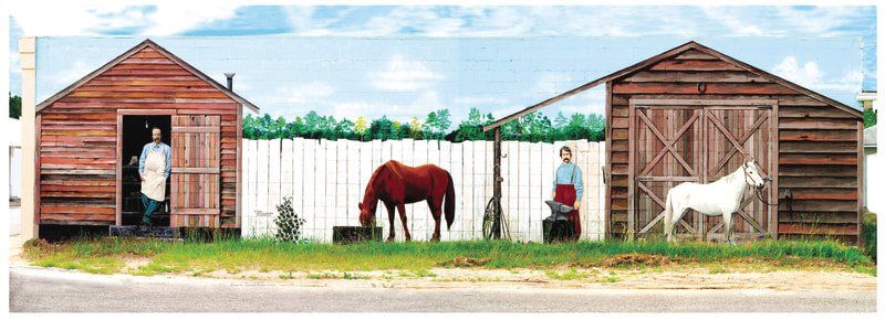 A couple of horses are standing in front of a wooden shed.