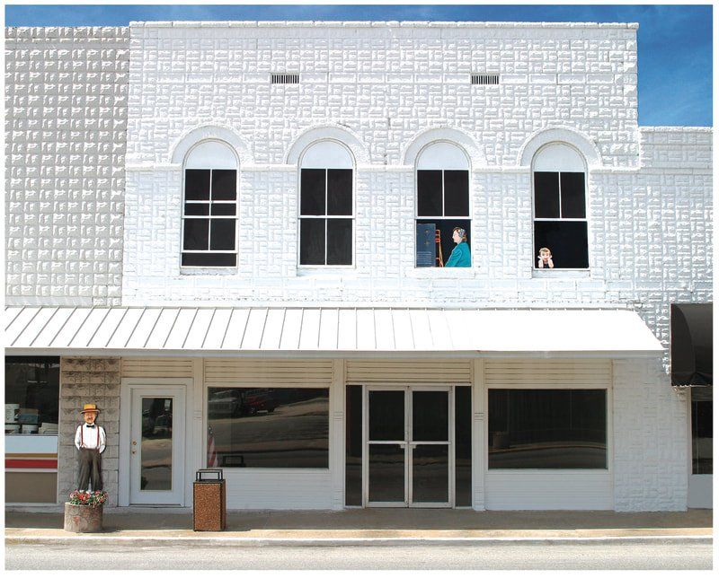 A white building with a statue of a man standing in front of it