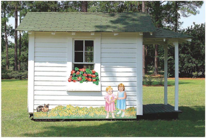 A white house with a green roof and two girls on the side