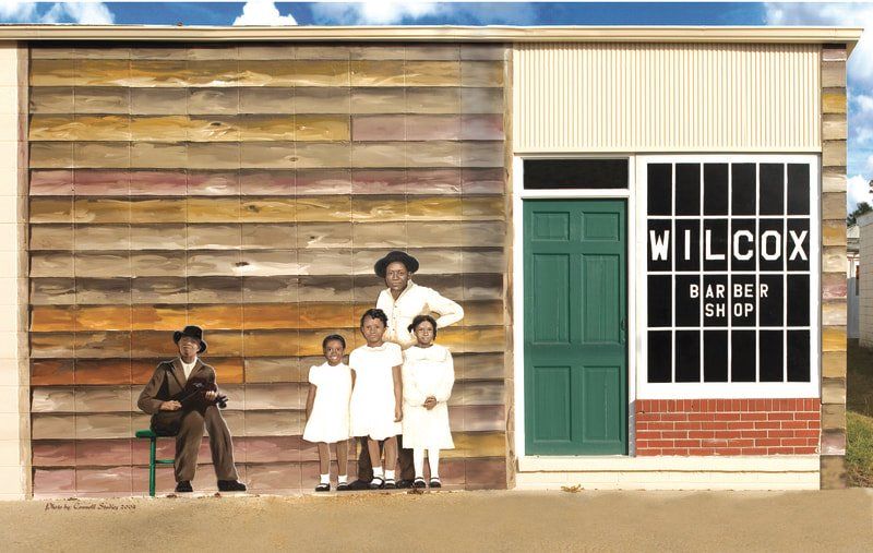 A family standing in front of a building that says wilcox barber shop