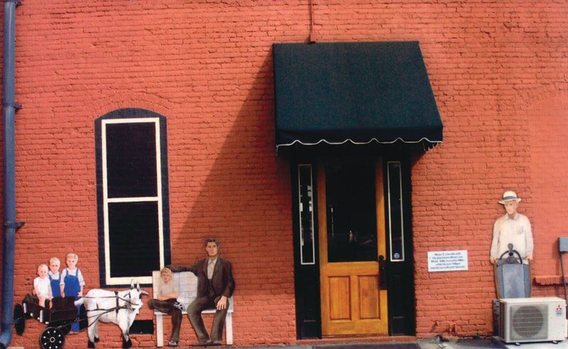 A red brick building has a black awning over the door