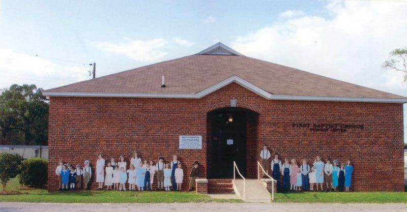 A group of people are standing in front of a brick building.