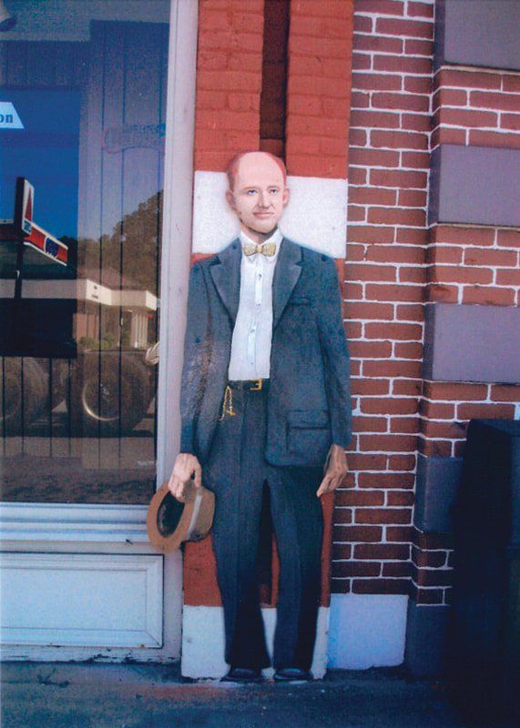 A man in a suit is standing in front of a brick building