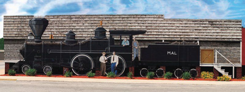 A large black train is painted on the side of a building.