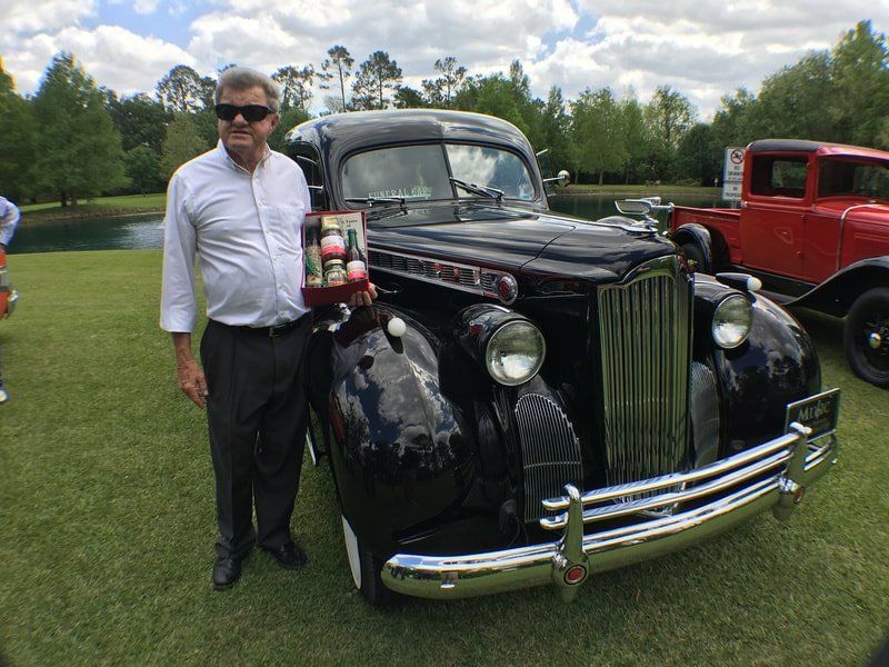 A man is standing in front of an old black car