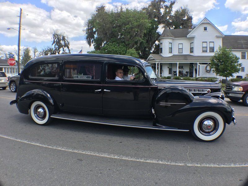 A black car with white tires is driving down a street